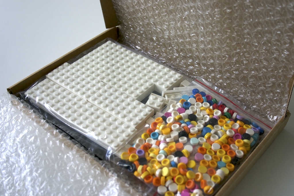 Smiley Brick Art Kit open box, with bubble wrap opened, showing the pieces inside.